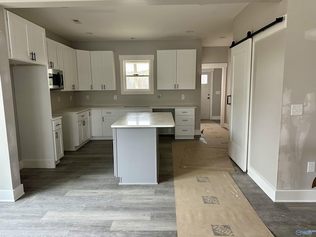 kitchen with a barn door, white cabinets, a kitchen island, and light wood-type flooring