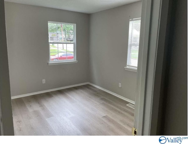 unfurnished room featuring light wood-style floors, visible vents, and baseboards