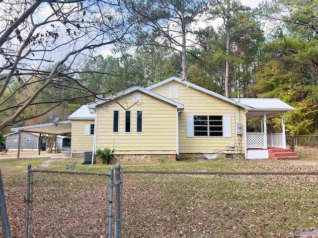 view of side of home with covered porch, a yard, cooling unit, and a carport