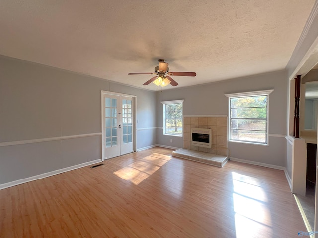 unfurnished living room with french doors, heating unit, light wood-type flooring, a textured ceiling, and ceiling fan