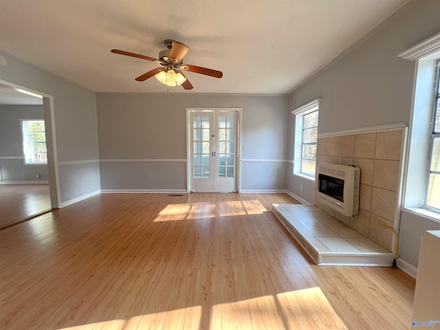 unfurnished living room with french doors, heating unit, plenty of natural light, and light wood-type flooring