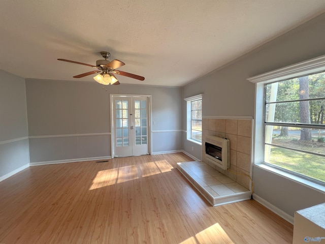 unfurnished living room featuring a wealth of natural light, heating unit, light wood-type flooring, and ceiling fan