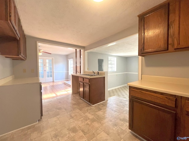 kitchen with electric panel, ceiling fan, a textured ceiling, french doors, and sink