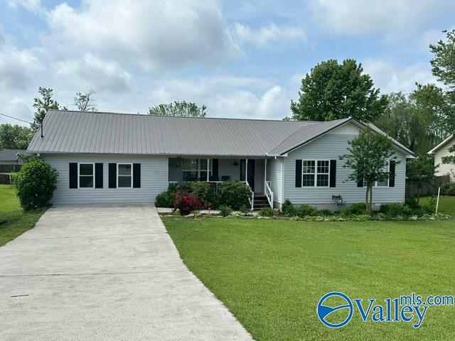 single story home featuring covered porch, concrete driveway, metal roof, and a front yard