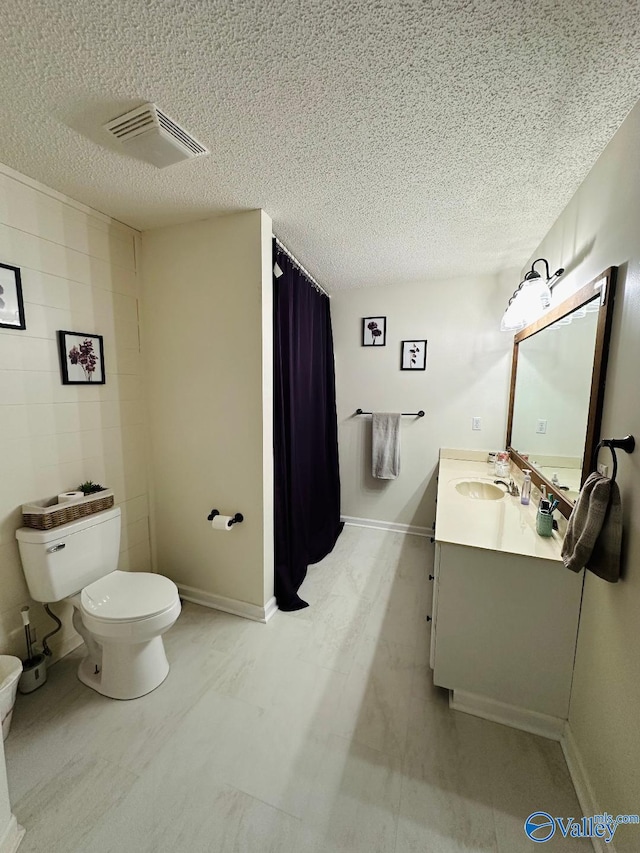 bathroom with a textured ceiling, toilet, vanity, visible vents, and baseboards