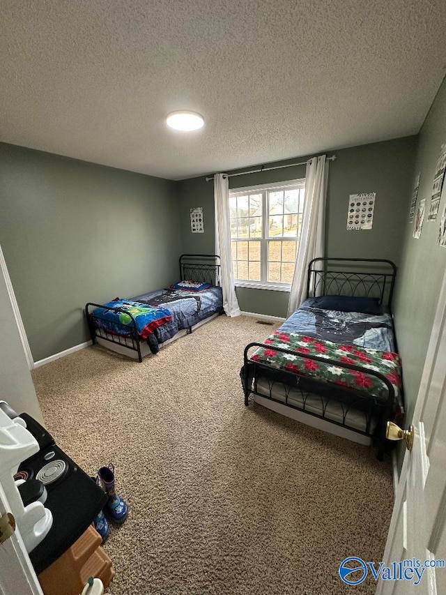 bedroom featuring a textured ceiling, carpet, and baseboards