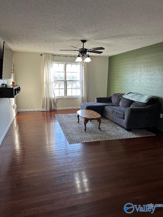 living room with dark wood finished floors, ceiling fan, a textured ceiling, and baseboards