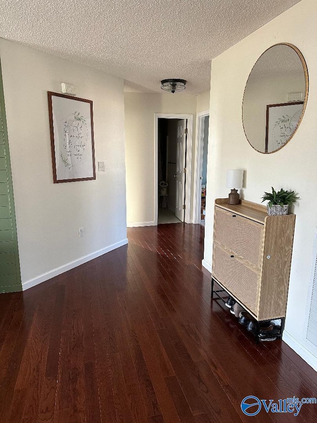 interior space with dark wood-style floors, a textured ceiling, and baseboards