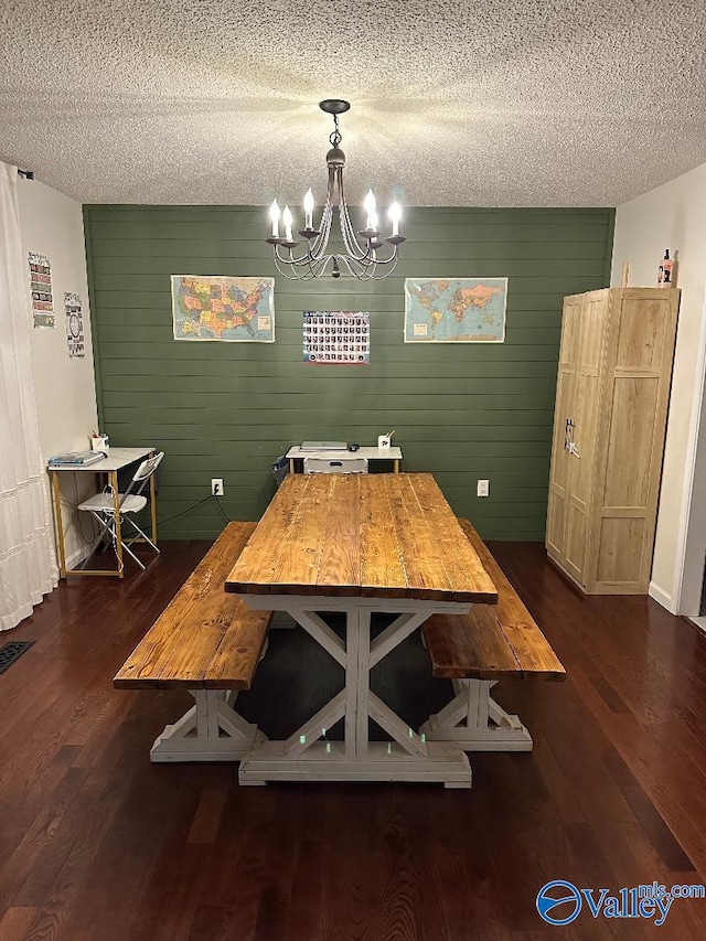 dining area featuring dark wood-style flooring, visible vents, a notable chandelier, and a textured ceiling