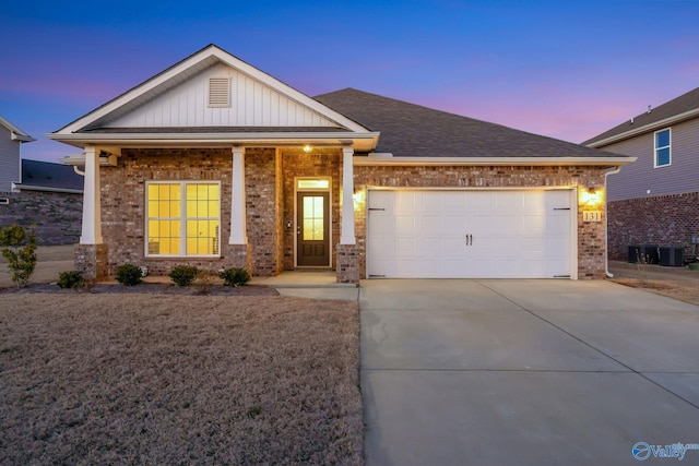 view of front of property with driveway, a shingled roof, an attached garage, board and batten siding, and brick siding