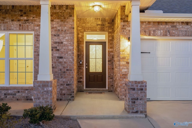 property entrance featuring an attached garage, covered porch, and brick siding