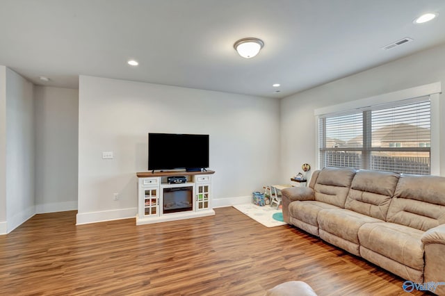 living room with baseboards, visible vents, and wood finished floors