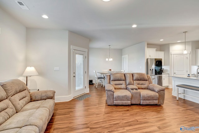 living room with recessed lighting, visible vents, light wood-style flooring, and baseboards