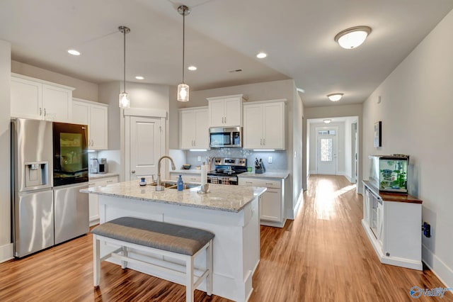 kitchen with stainless steel appliances, decorative backsplash, light wood-style floors, white cabinetry, and a sink