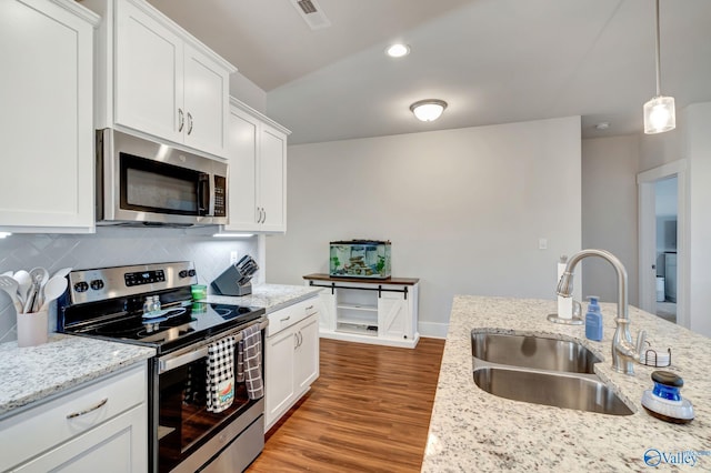 kitchen featuring visible vents, decorative backsplash, wood finished floors, stainless steel appliances, and a sink