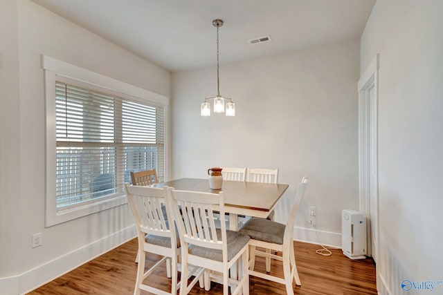 dining area featuring a notable chandelier, wood finished floors, visible vents, and baseboards