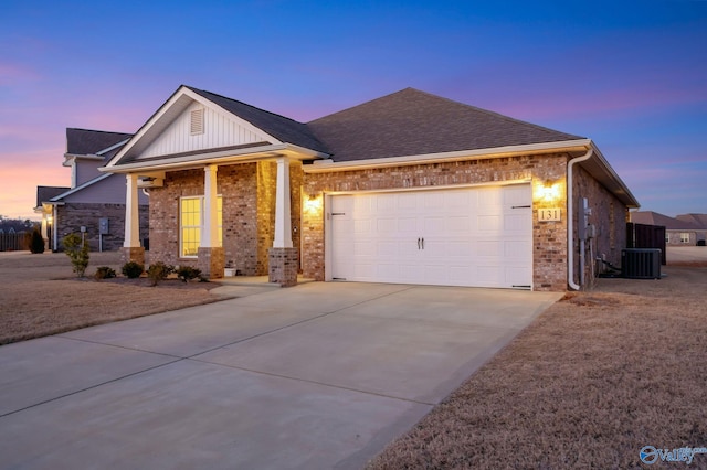 view of front of house featuring central AC unit, an attached garage, brick siding, concrete driveway, and board and batten siding