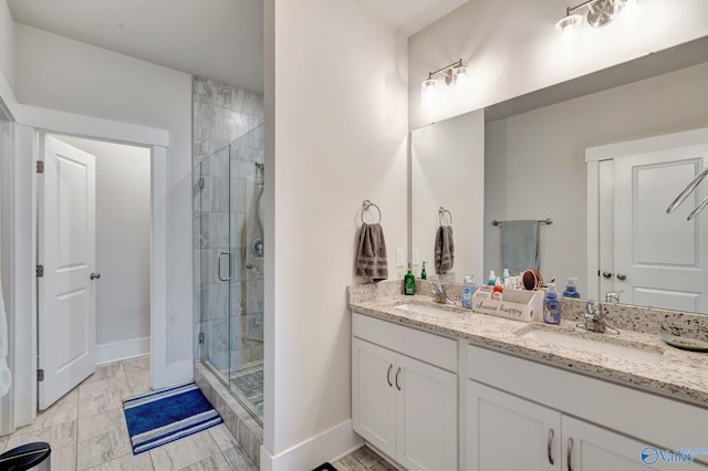 full bath featuring double vanity, a shower stall, baseboards, and a sink