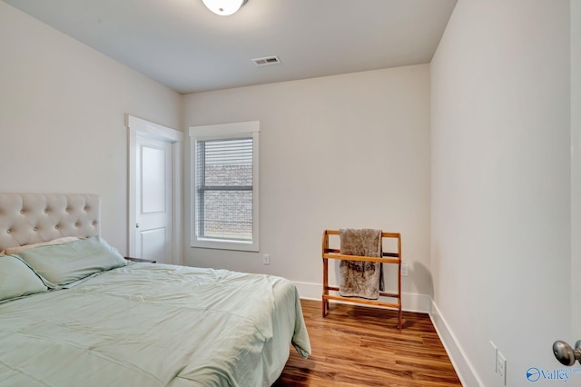 bedroom featuring wood finished floors, visible vents, and baseboards