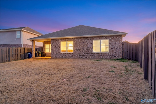 back of property featuring a shingled roof, brick siding, and a fenced backyard