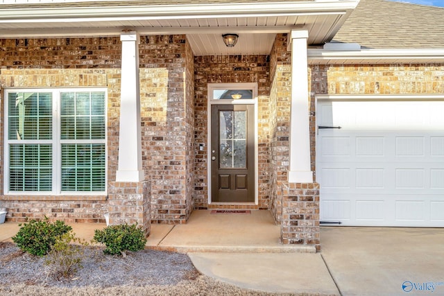 entrance to property featuring a shingled roof, brick siding, and an attached garage