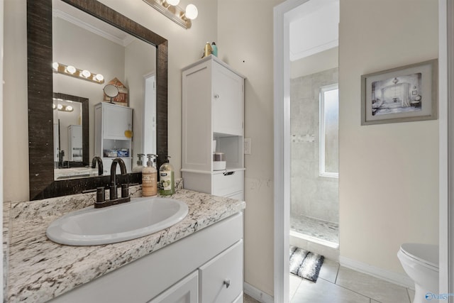 bathroom with tiled shower, tile patterned flooring, toilet, vanity, and baseboards