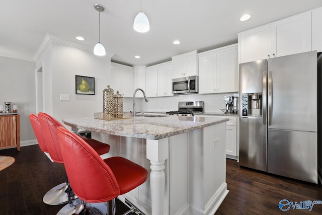 kitchen with hanging light fixtures, sink, white cabinetry, a center island with sink, and stainless steel appliances