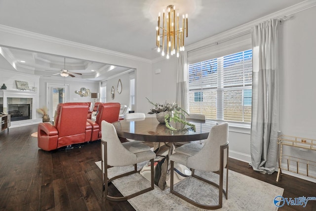 dining room with crown molding, a tiled fireplace, ceiling fan with notable chandelier, and dark hardwood / wood-style floors