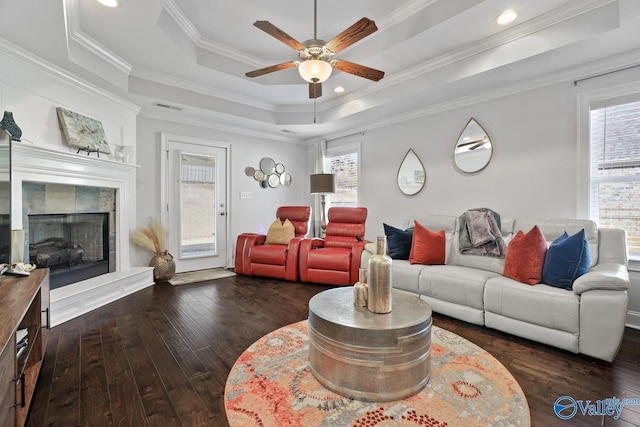 living room featuring crown molding, dark hardwood / wood-style flooring, ceiling fan, and a raised ceiling