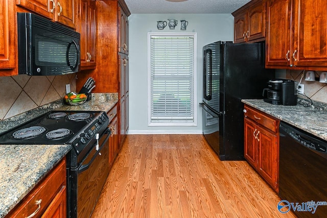 kitchen featuring black appliances, a textured ceiling, and light hardwood / wood-style flooring