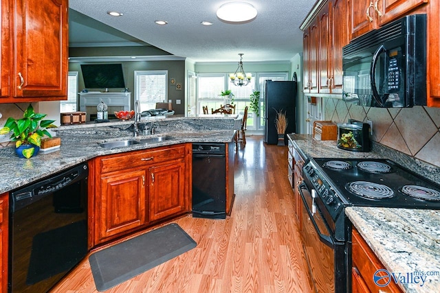 kitchen with light wood-type flooring, tasteful backsplash, sink, black appliances, and an inviting chandelier