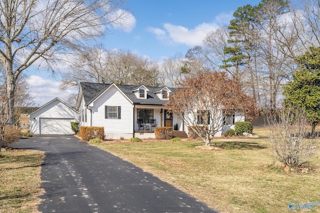 cape cod-style house featuring an outbuilding, covered porch, a detached garage, roof with shingles, and a front yard