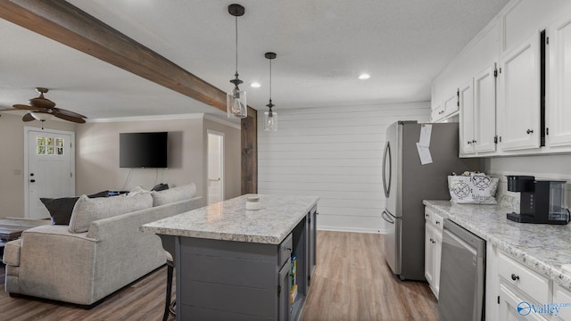 kitchen with stainless steel appliances, a center island, open floor plan, white cabinetry, and a ceiling fan