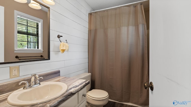 full bathroom featuring a shower with shower curtain, wooden walls, toilet, and vanity