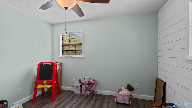 rec room with baseboards, a ceiling fan, wood finished floors, and a textured ceiling