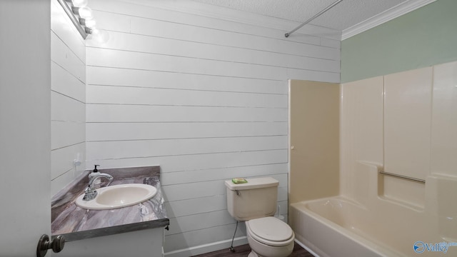 bathroom with wood walls, toilet, vanity, crown molding, and a textured ceiling