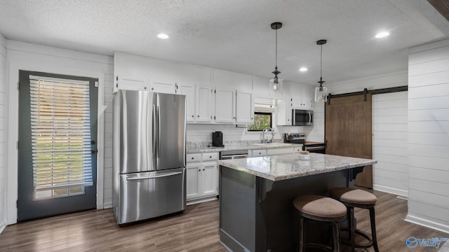 kitchen featuring dark wood finished floors, stainless steel appliances, a kitchen island, a textured ceiling, and white cabinetry
