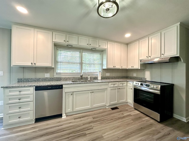 kitchen with stainless steel appliances, white cabinetry, sink, and light stone counters