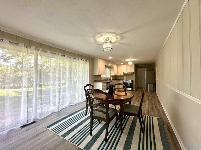 dining area with a textured ceiling and light hardwood / wood-style floors