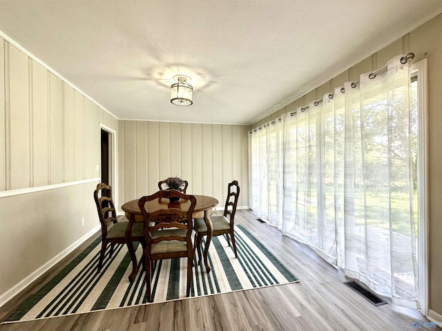 dining room with hardwood / wood-style flooring, crown molding, and a textured ceiling