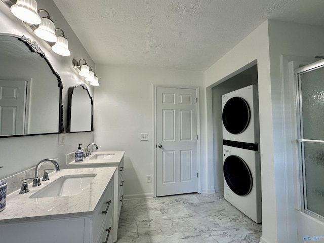 bathroom featuring stacked washer and clothes dryer, a shower with door, vanity, and a textured ceiling