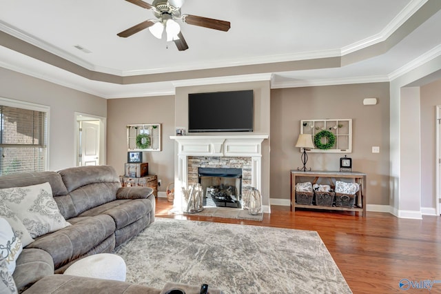 living room featuring a fireplace, visible vents, a raised ceiling, and wood finished floors