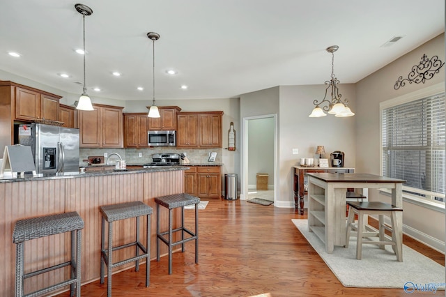 kitchen with brown cabinets, visible vents, stainless steel appliances, and hanging light fixtures