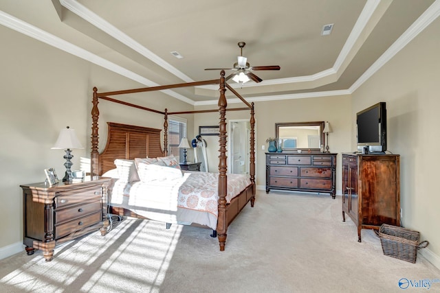 bedroom with a tray ceiling, light colored carpet, and baseboards