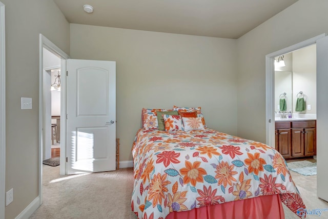 bedroom with light carpet, ensuite bath, and baseboards