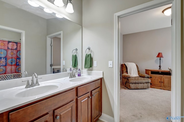 full bath with double vanity, baseboards, and a sink