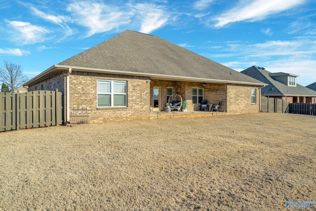 back of property featuring a patio area, a shingled roof, fence, and brick siding