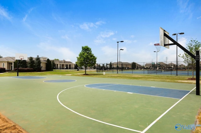 view of basketball court featuring a tennis court, a residential view, community basketball court, and fence