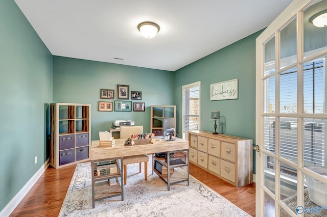 office featuring light wood finished floors, visible vents, and baseboards