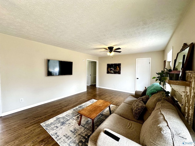 living room with a fireplace with raised hearth, ceiling fan, dark wood-style flooring, and baseboards